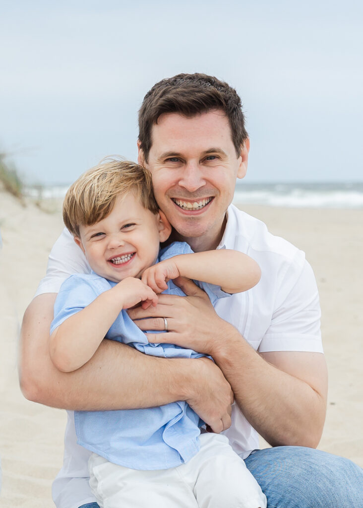 Smiling dad on a Jersey shore beach with his son